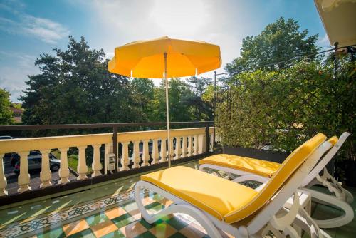 a yellow chair and an umbrella on a balcony at Terme Preistoriche Resort & Spa in Montegrotto Terme