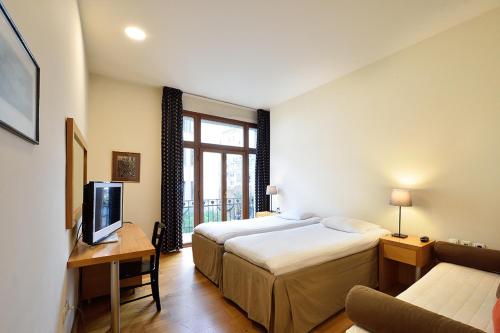 テッサロニキにあるLe Palace Hotelのベッド2台とテレビが備わるホテルルームです。