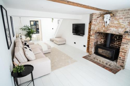 a living room with a white couch and a brick fireplace at The Scandi Cottage in Theydon Bois