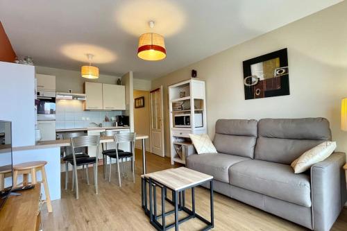 un salon avec un canapé et une cuisine dans l'établissement Appartement MerliDunes Proche de la plage, à Merlimont