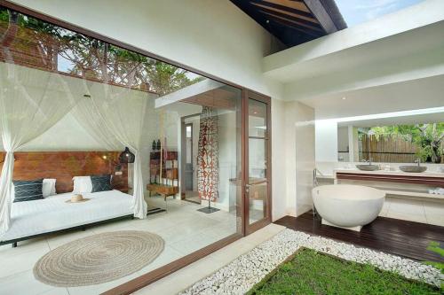 a bathroom with a tub and a bed and a bath room at Villa Bengawan in Canggu