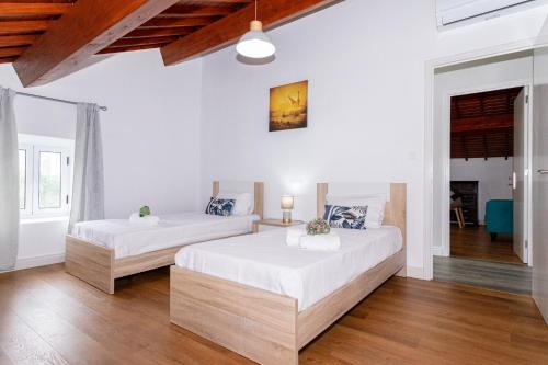 two beds in a room with white walls and wooden floors at Oásis Fonte Grande in Santo António