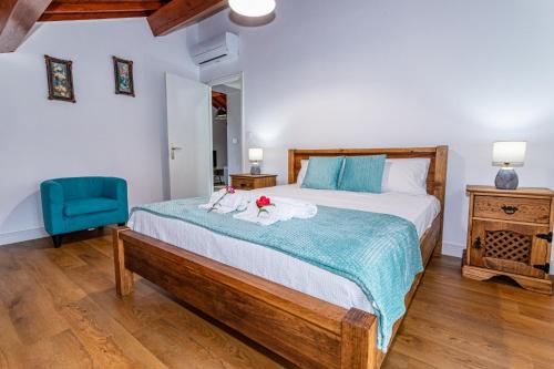 a bedroom with a large bed and a blue chair at Oásis Fonte Grande in Santo António