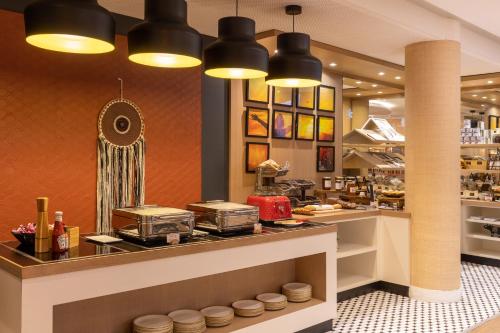 a restaurant with a counter with some food at Aiden by Best Western Paris Roissy CDG in Roissy-en-France