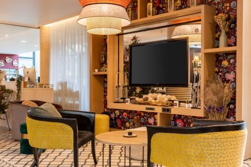 a living room with a tv and a table and chairs at Aiden by Best Western Paris Roissy CDG in Roissy-en-France