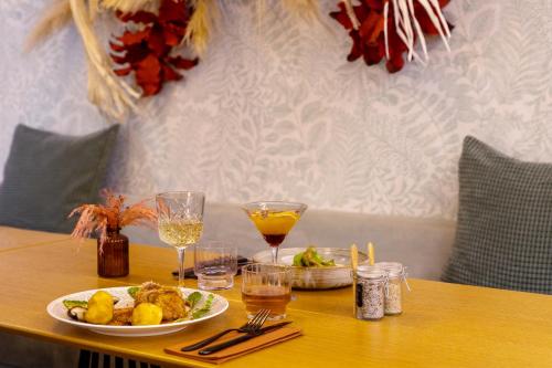 a table with a plate of food and glasses of wine at Aiden by Best Western Paris Roissy CDG in Roissy-en-France