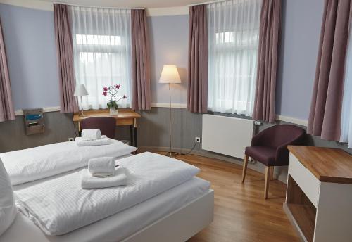 a hotel room with two beds and a desk at Schönblick. Christliches Gästezentrum in Schwäbisch Gmünd