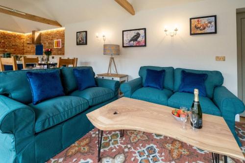 a living room with blue couches and a table at Alde Bay Farm - Oyster Catcher in Aldeburgh
