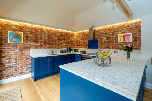 a kitchen with blue cabinets and a brick wall at Alde Bay Farm - Oyster Catcher in Aldeburgh