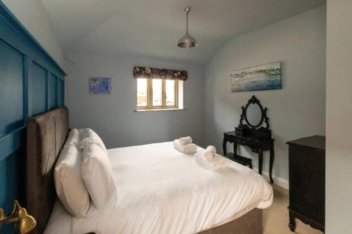 a bedroom with a bed with white sheets and a mirror at Alde Bay Farm - Oyster Catcher in Aldeburgh