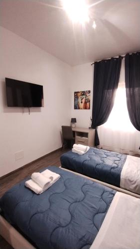 ローマにあるAppartamento Fiore Roma San Pietroのベッド2台、壁掛けテレビが備わる客室です。