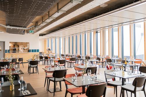 una sala da pranzo con tavoli, sedie e finestre di Afterwork Hotel a Etoy