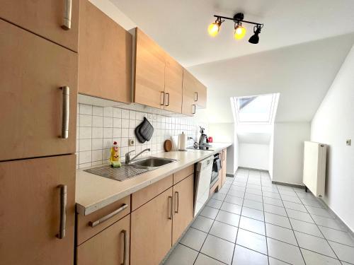 a kitchen with a sink and a refrigerator at favstay Industrialstyle 2-Zimmer 60qm mit Balkon, Panarbora Fernblick, 55" TV & Netflix, 55Mbit WLAN, Parkplatz in Waldbröl