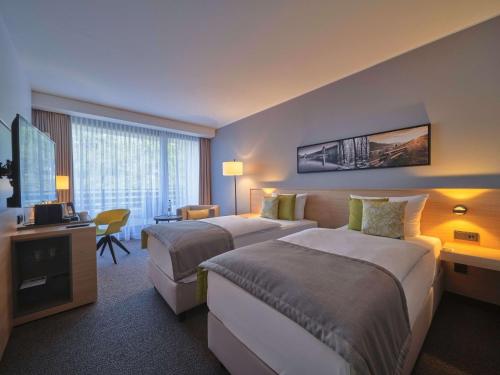 a hotel room with two beds and a television at Dorint Hotel & Sportresort Arnsberg/Sauerland in Neheim-Hüsten