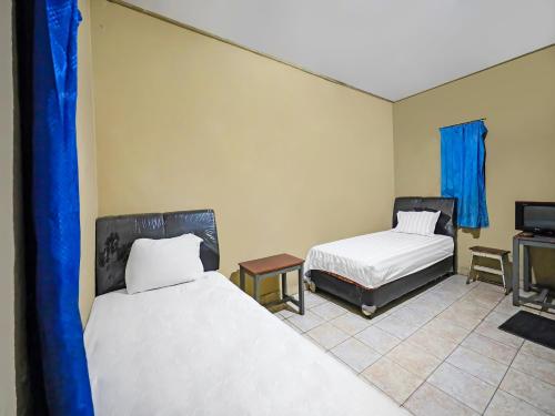 a room with two beds and a tv in it at OYO 92230 Penginapan Metro Parepare in Parepare