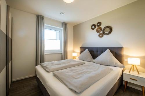 Schlafzimmer mit einem großen weißen Bett und einem Fenster in der Unterkunft Haus Strandläufer Apartment 2 2 Küstennebel in Büsum