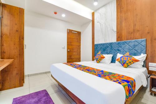 a bedroom with a large white bed with a blue headboard at FabHotel Elite Inn I in Ahmedabad