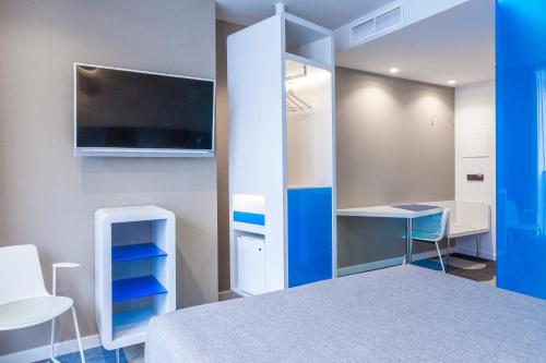 a bedroom with a bed and a mirror and a desk at Hotel Macià Sevilla Kubb in Seville