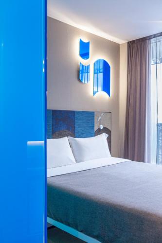 a bedroom with a large bed with blue accents at Hotel Macià Sevilla Kubb in Seville