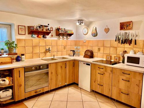 eine große Küche mit Holzschränken und einer Mikrowelle in der Unterkunft AEDA chalupa in Liptovské Sliače