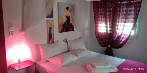 a bedroom with a white bed with pink lighting at Sevi Platamon Home in Platamonas
