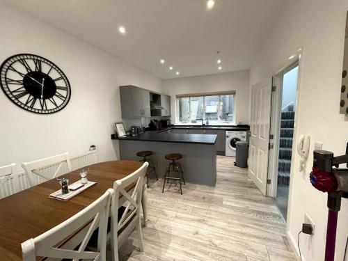 a kitchen and dining room with a table and a clock on the wall at 'Hidden Jewel' city centre + FREE PARKING in Plymouth