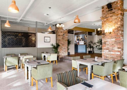 a restaurant with tables and chairs and a brick wall at Dragonfly Hotel Colchester in Colchester