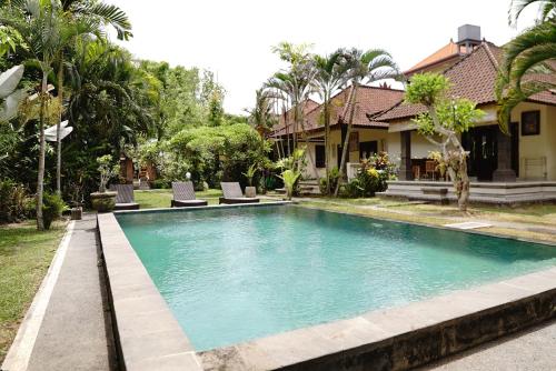 a swimming pool in front of a house at Alit Bungalow & Warung in Ubud