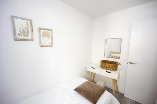 Habitación blanca con cama y espejo en Casa Poulo Padrón, en Padrón