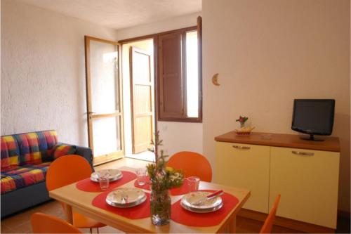 een woonkamer met een tafel en stoelen en een televisie bij Primavera Apartments in Capo Testa
