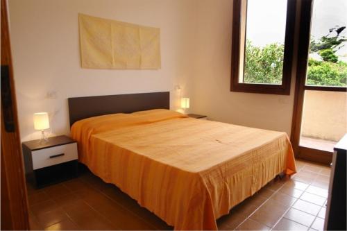 1 dormitorio con 1 cama grande con colcha de color naranja en Primavera Apartments en Capo Testa