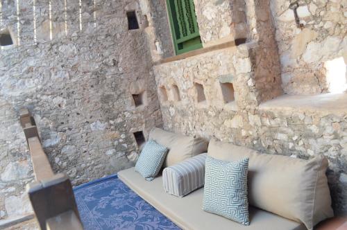 a couch with pillows sitting next to a stone wall at Casa Muse Kastellorizo Whole House in Meyisti