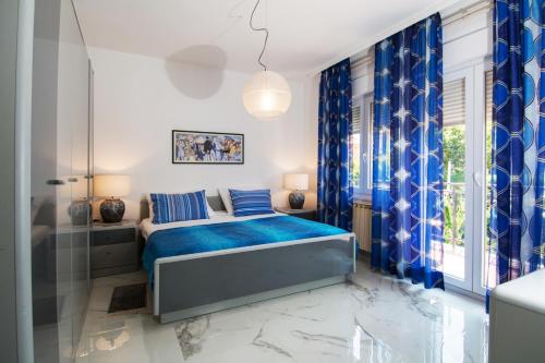 een slaapkamer met een bed, blauwe gordijnen en een raam bij Apartment Lala & Nina in Banjole