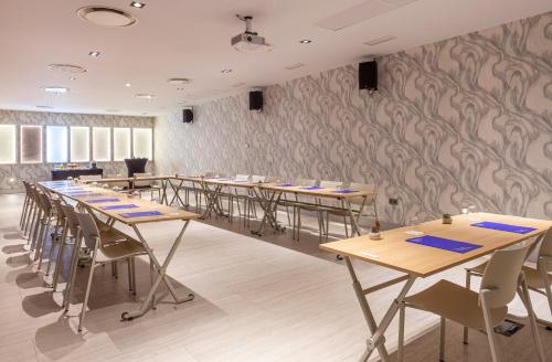 a row of tables and chairs in a room with wallpaper at Hotel Macià Sevilla Kubb in Seville