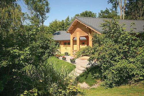 a wooden house with a porch and a yard at Camping 't Ol Gat in Zoutkamp