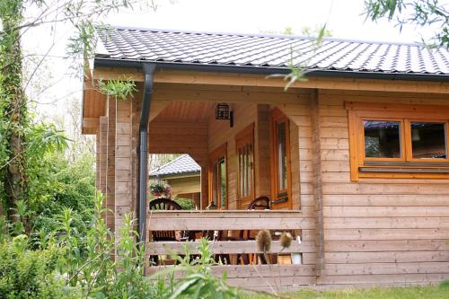 a small wooden house with a porch and a window at Camping 't Ol Gat in Zoutkamp