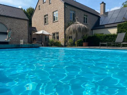 a swimming pool in front of a house at Cosy Studio met Zwembad in Beringen