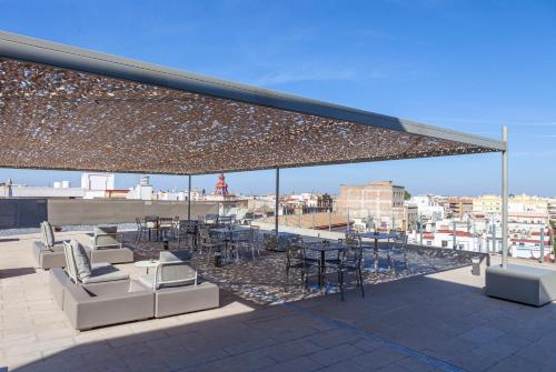 a patio with chairs and tables on a roof at Hotel Macià Sevilla Kubb in Seville