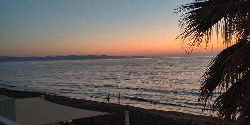 a sunset on a beach with the ocean at Uniquely located on the beach in Ayia Marina
