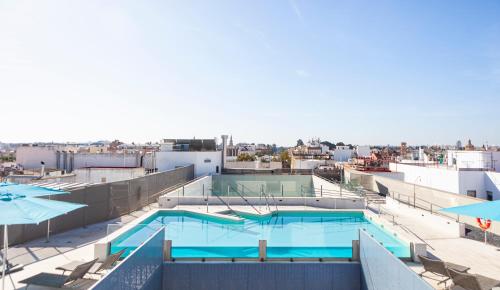 a swimming pool on top of a building with umbrellas at Hotel Macià Sevilla Kubb in Seville