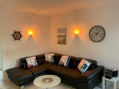 a living room with a couch and a clock on the wall at Austernfischer - Haus 12 in Lenste