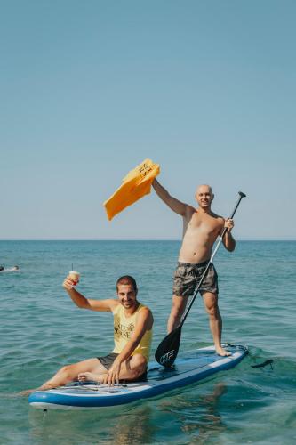 two men on a paddle board in the water at Villa Yianna in Néa Meságkala