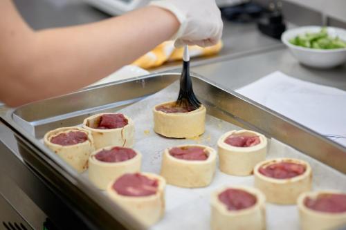 a person with a spatula cooking food on a tray at Evita Hotel & SPA in Tleń