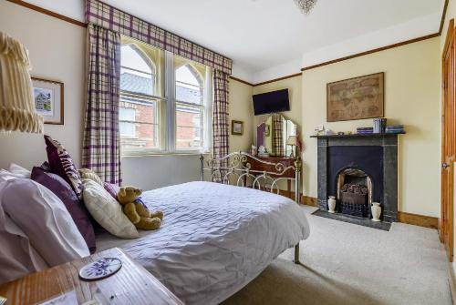 a teddy bear sitting on a bed in a bedroom with a fireplace at Roscrea Bed & Breakfast in Bodmin