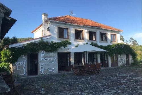 a house with a table and an umbrella at Casa de São Cristóvão - 4r and private swimmingpool in Vila de Punhe