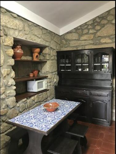a kitchen with a table and a stone wall at Casa de São Cristóvão - 4r and private swimmingpool in Vila de Punhe