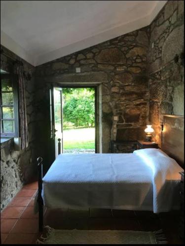 a bedroom with a blue bed in a stone wall at Casa de São Cristóvão - 4r and private swimmingpool in Vila de Punhe