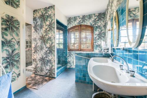 ein Badezimmer mit blau gefliesten Wänden und einer weißen Badewanne in der Unterkunft Mas Frederi - Maison avec piscine pour 10 in Paradou