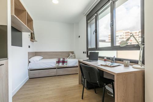 a bedroom with a desk and a bed with a laptop at micampus Madrid Sinesio Delgado Student Residence in Madrid
