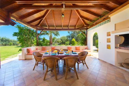 an outdoor dining room with a table and chairs at Villa Amelia in Gennadi